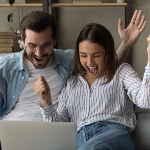 Euphoric couple cheerful male female read unbelievable Google bonus Digitalspot kod news on laptop